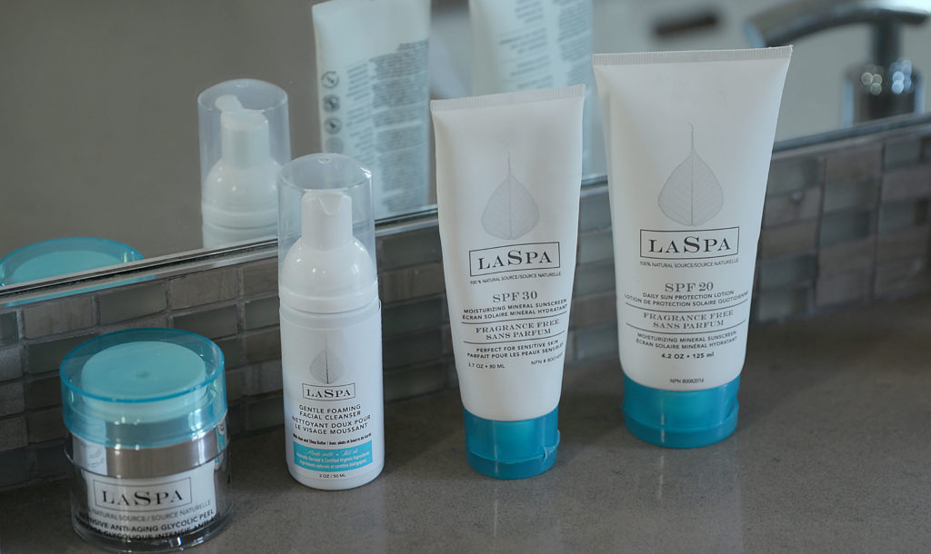 LASPA Gentle Foaming Cleanser Bottle with Blue Lid with other LASPA skincare containers lined up on a dark marble bathroom counter