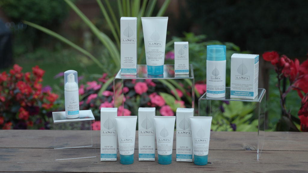 All LAPSA Naturals skincare products lined up in a group shot shown in white and blue packaging, with a natural background setting.