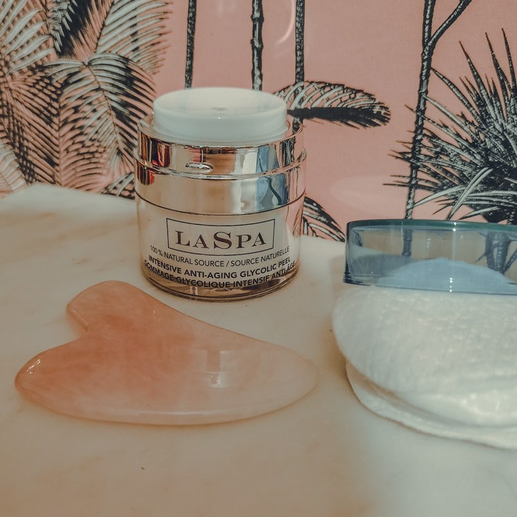 A white jar of face acid treatment on a white-pink marble countertop